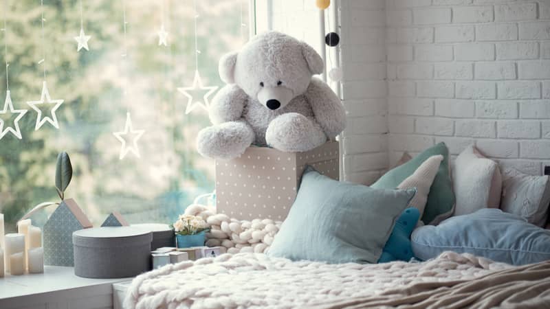 cozy children's room in bright soft colors, pillows and a blanket are lying on the bed