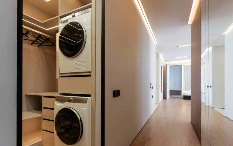 a small laundry room with front load washer and dryer stacked