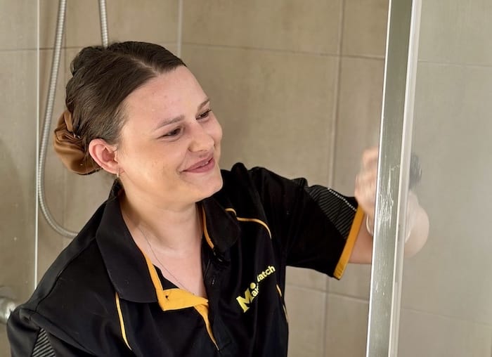 Alison smiling while cleaning the shower