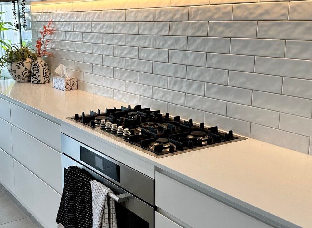 Black stove top grates in a clean kitchen setup with tiled backsplash