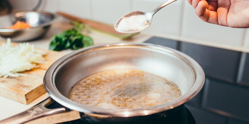 cleaning a burnt pan with a spoonful of baking soda