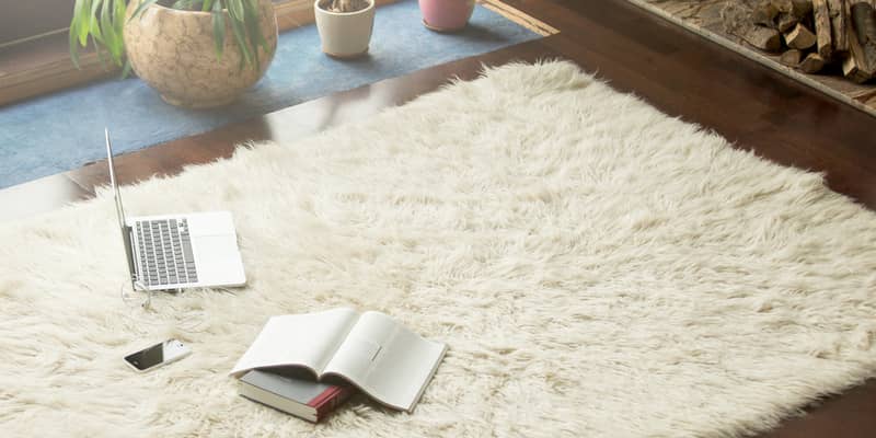 Books, smartphone and laptop lying on white carpet in modern luxury living room interior