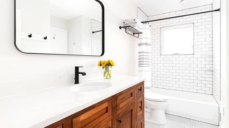 bathroom with a wood cabinet, marble countertop, and subway tile shower.