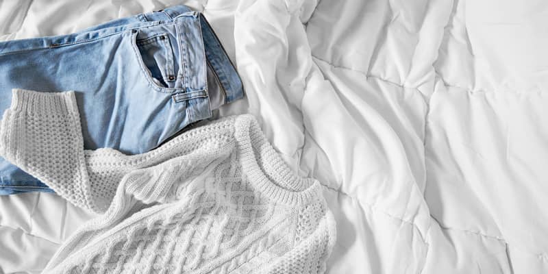 Female clothes laid out on bed, morning light