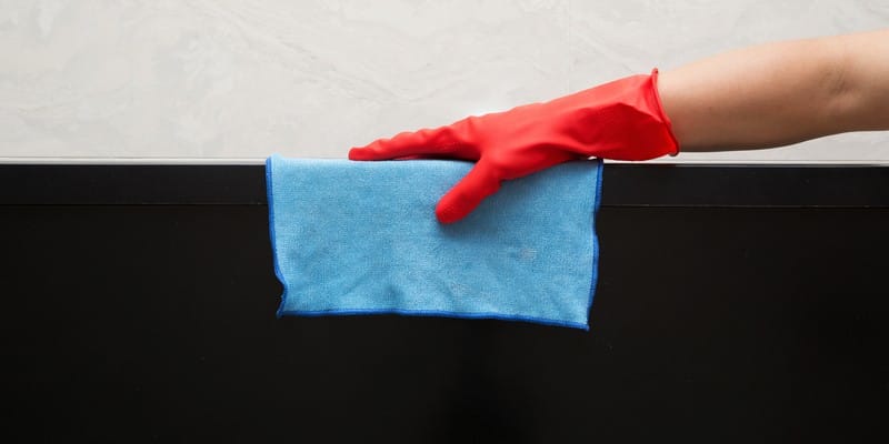 man in red rubber gloves cleaning tv with blue cloth