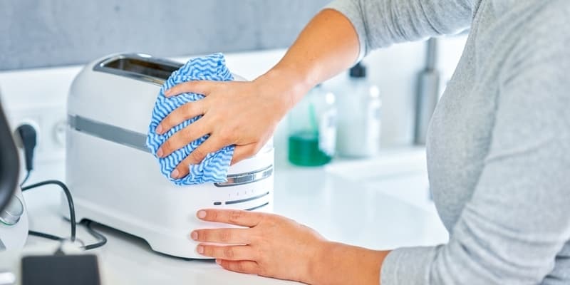 Woman cleaning the toaster machine in the kitchen