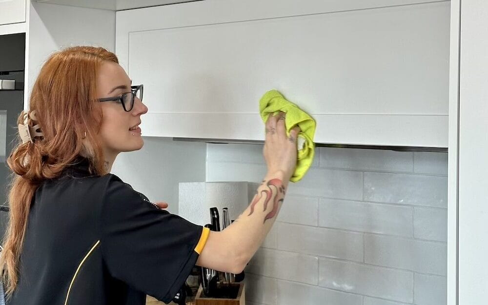 Professional cleaner wiping kitchen cabinet grease