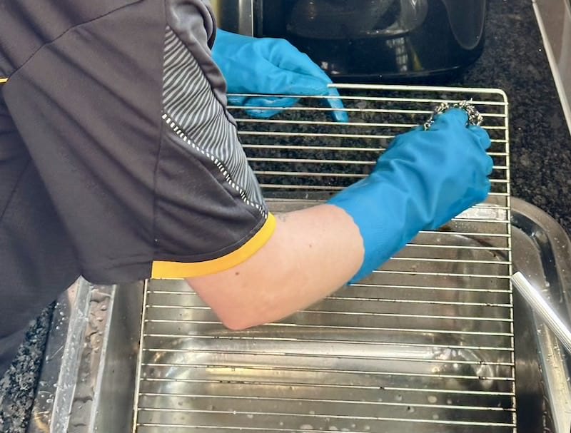 cleaning an oven rack in the sink