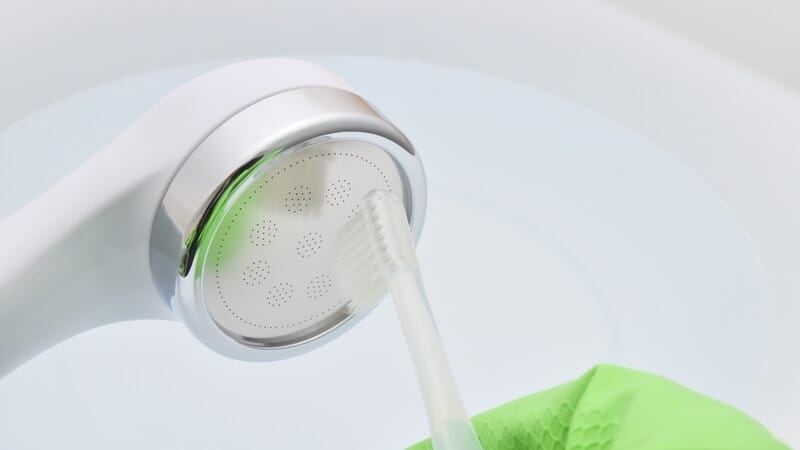 cleaning shower head with toothbrush