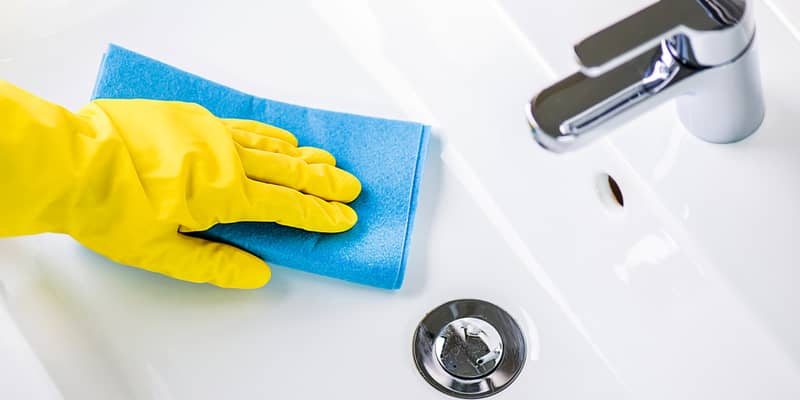 woman cleaning modern new basin in bathroom