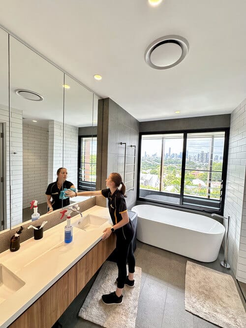 Maid2Match cleaner wiping down a bathroom mirror in a customer's house