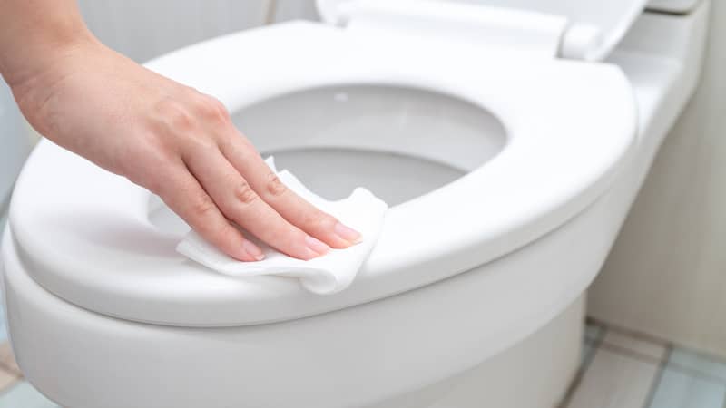 hand cleaning toilet seat by a wet wipe