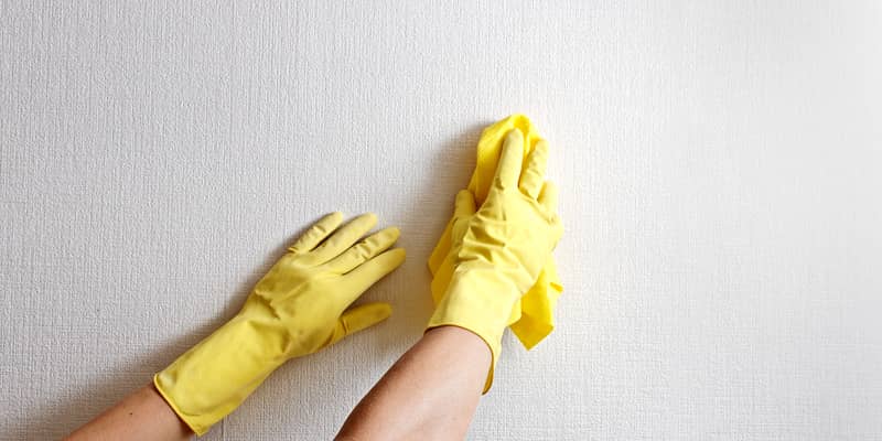 hands with yellow gloves clean wallpaper at home