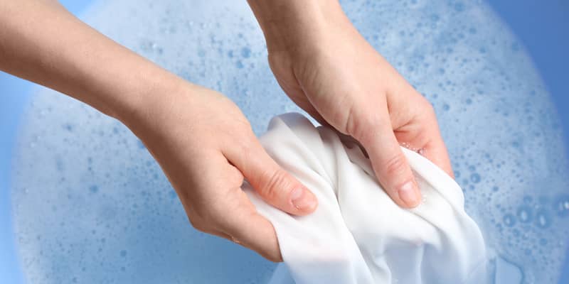 Top view of woman hand washing white clothing in suds