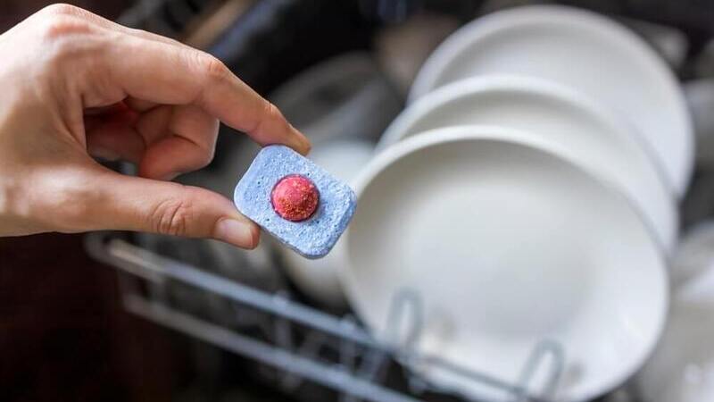 close up of hand holding dishwasher tablet