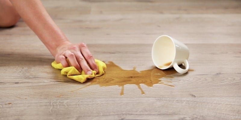 A cup of coffee fell on laminate, coffee spilled on floor.