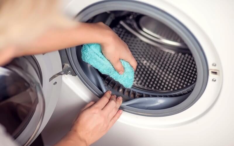 Hand wiping dirt under dryer door seal