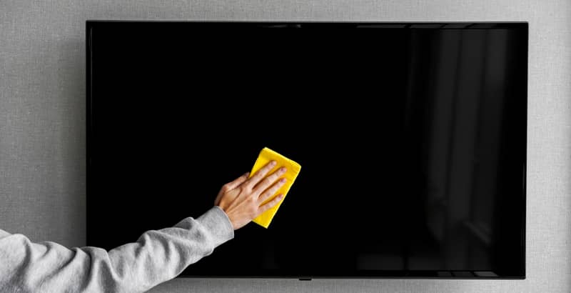 hand wipes dust from a plasma TV