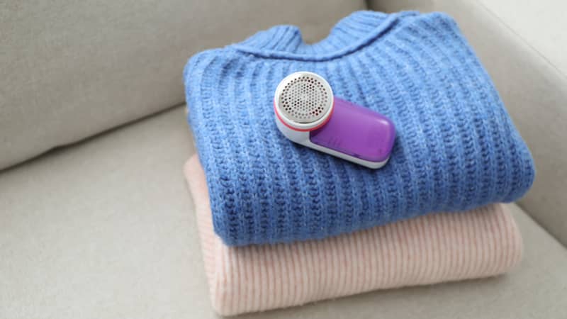 Modern fabric shaver and woolen sweaters on sofa