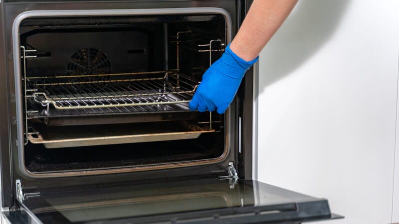 hand taking the rack from the oven for cleaning