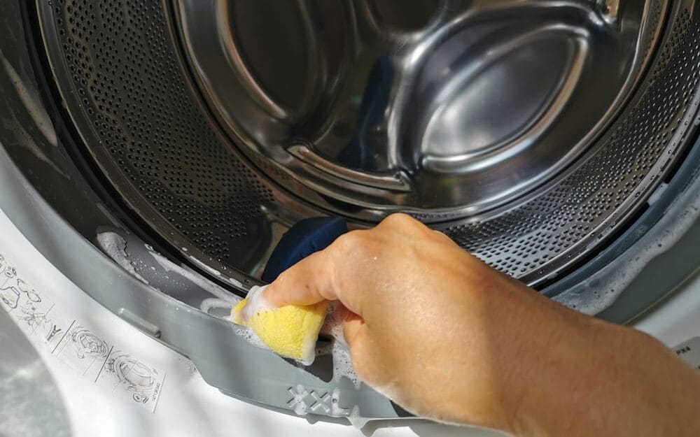 close up of hand using sponge and soap to clean dryer