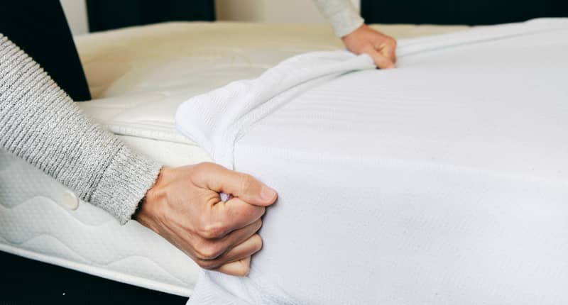 man hand removing mattress protector