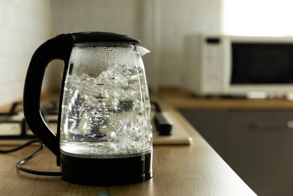 Modern electric transparent kettle on a wooden table in the kitchen.