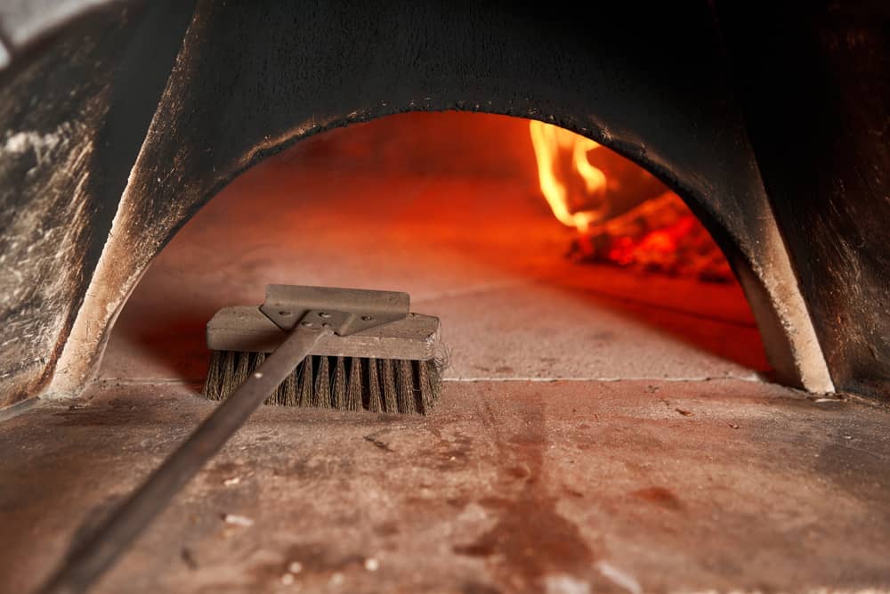 cleaning pizza oven with brush