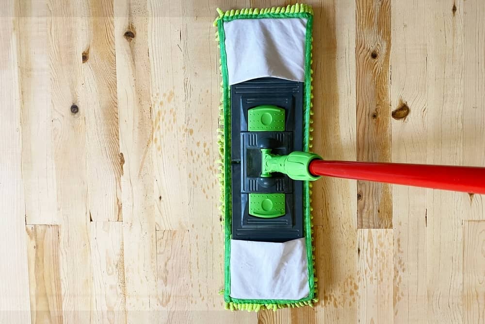 Cleaning wooden floor with mop, laminate floor top view.