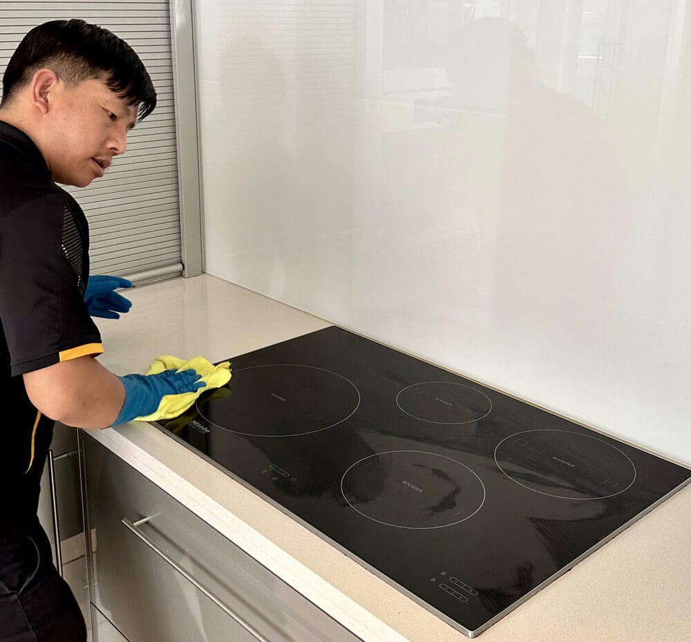 Professional cleaner wiping a stove top