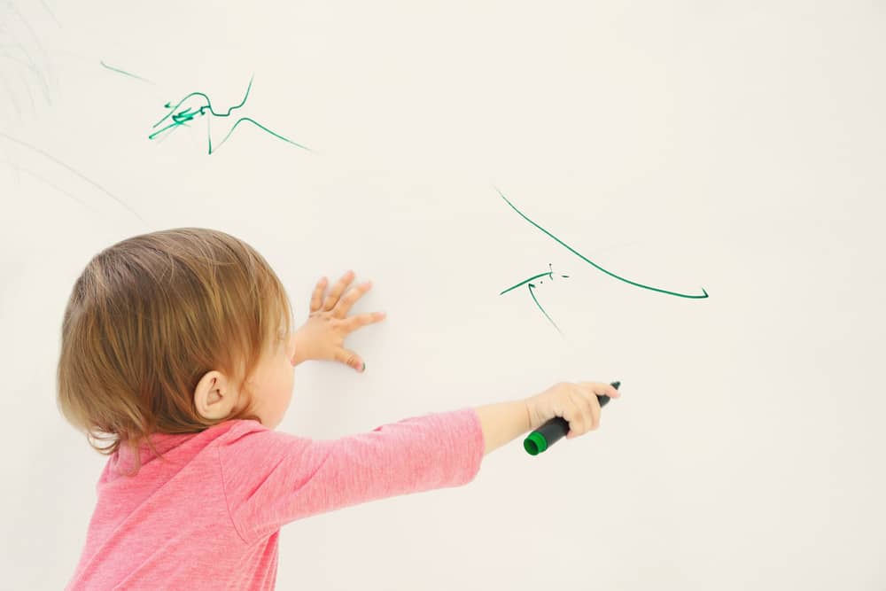 a child using a permanent marker to write on the wall