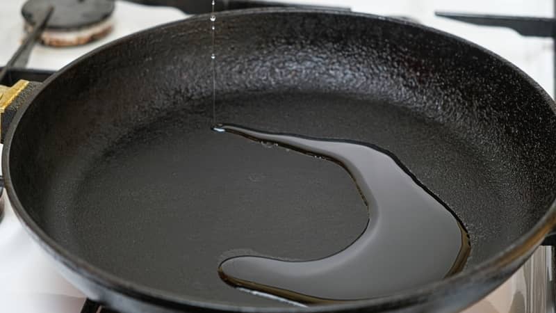 pouring vegetable oil into a cast iron pan