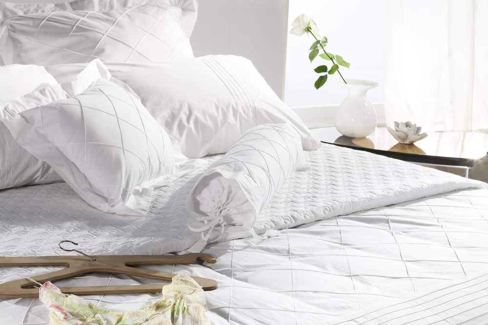 bed closeup , classy white covers , in sunny white bedroom