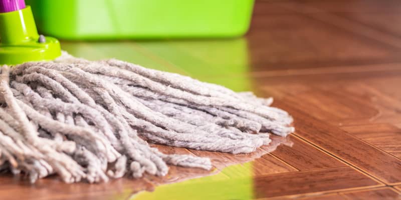 String mop on the tile floor and a puddle of water.