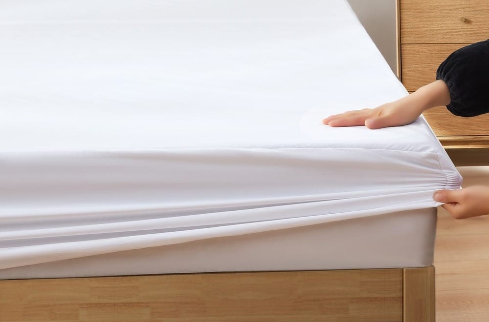 female hand putting mattress protector on a mattress