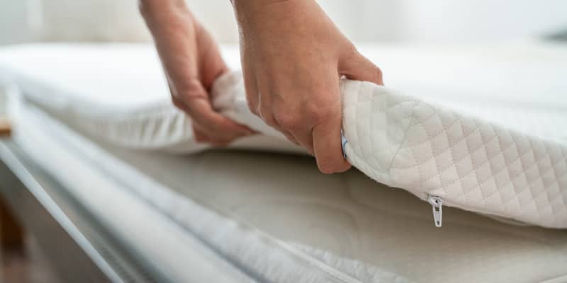 hands raising a memory foam mattress