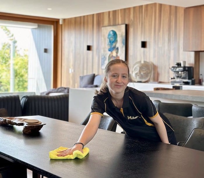 Maid2Match professional cleaner Jade smiling while wiping down a dining table