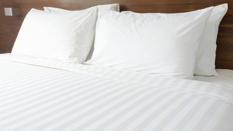 white pillow on bed with bedsheets