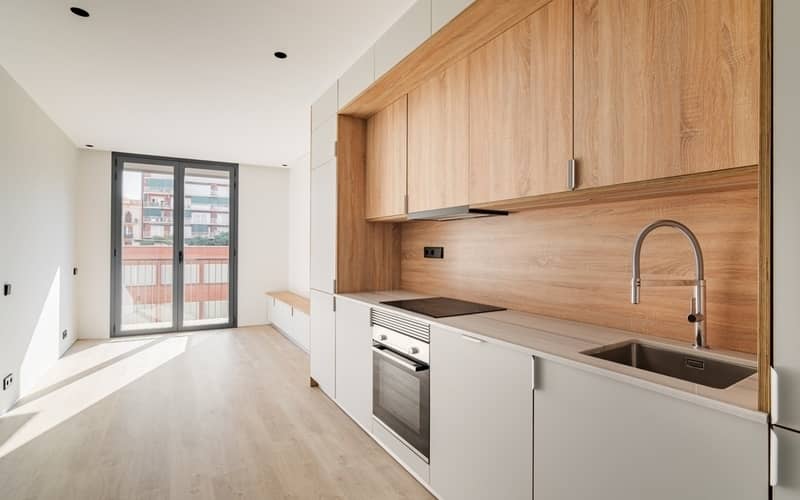 Contemporary minimal kitchen and living room with balcony at empty refurbished apartment.