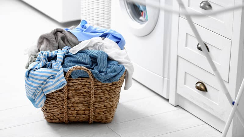 Wicker basket with dirty laundry on floor indoors