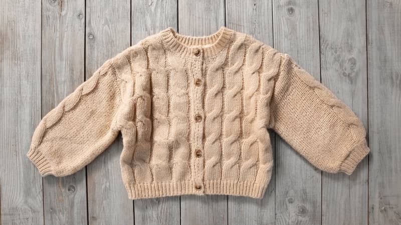 beige sweater laid flat on a wooden surface