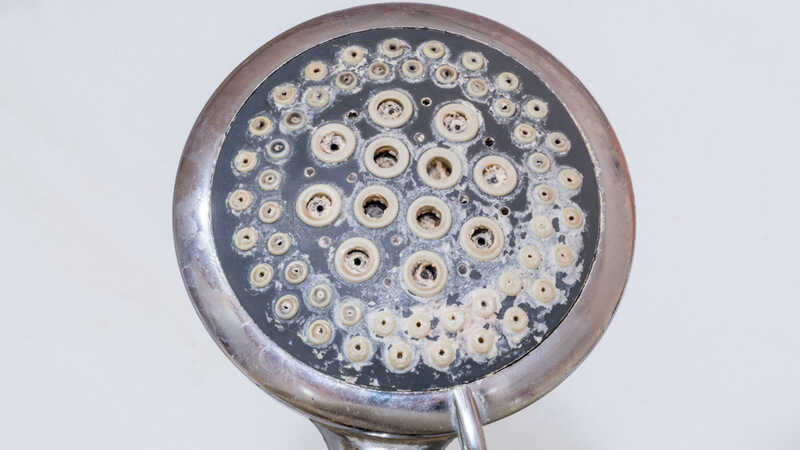 Close-up of limescale on shower head. Calcification of a shower head in bathroom.