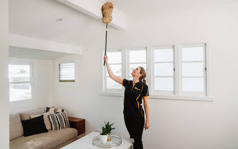 professional cleaner using a duster to clean the ceiling