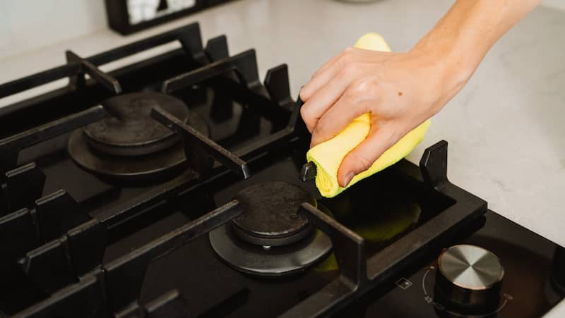 female hands cleaning the stovetop with a cloth