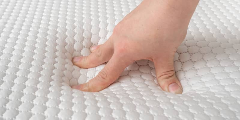 Hand of woman is testing memory foam mattress quality.