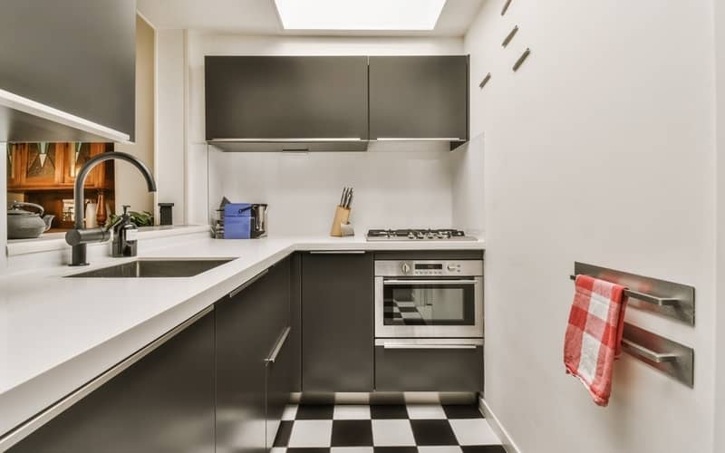 Black metal cabinets over the stove in a modern kitchen with checkered tiles