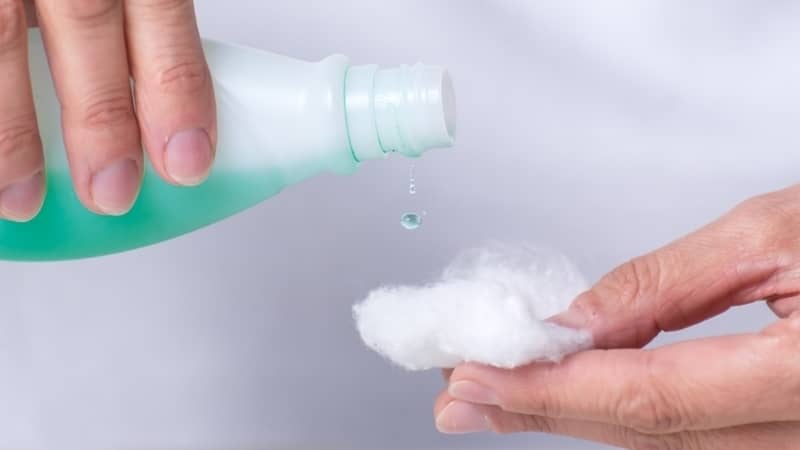 adult woman's hands putting nail polish remover on cotton