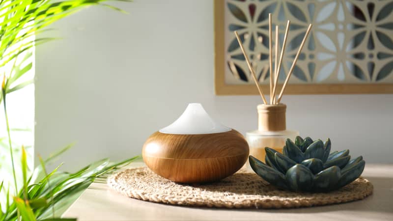 Aroma oil diffuser and reed air freshener on table in room