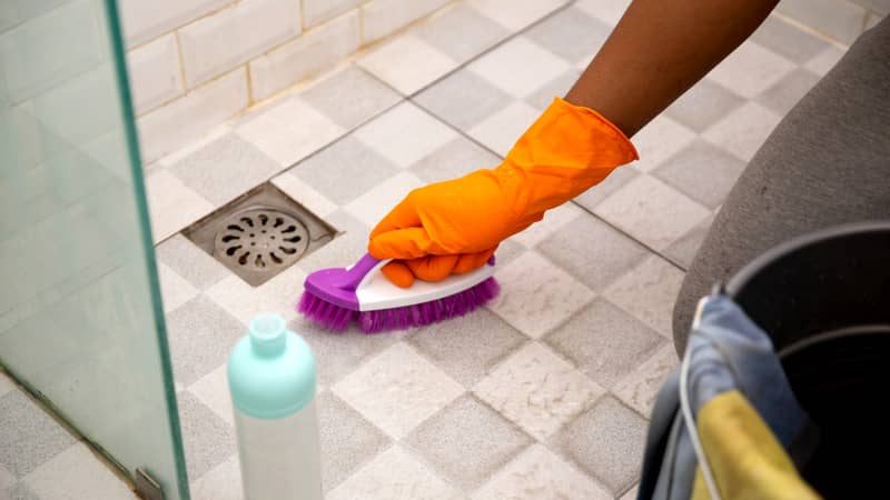 close up hand brushing toilet bathroom floor