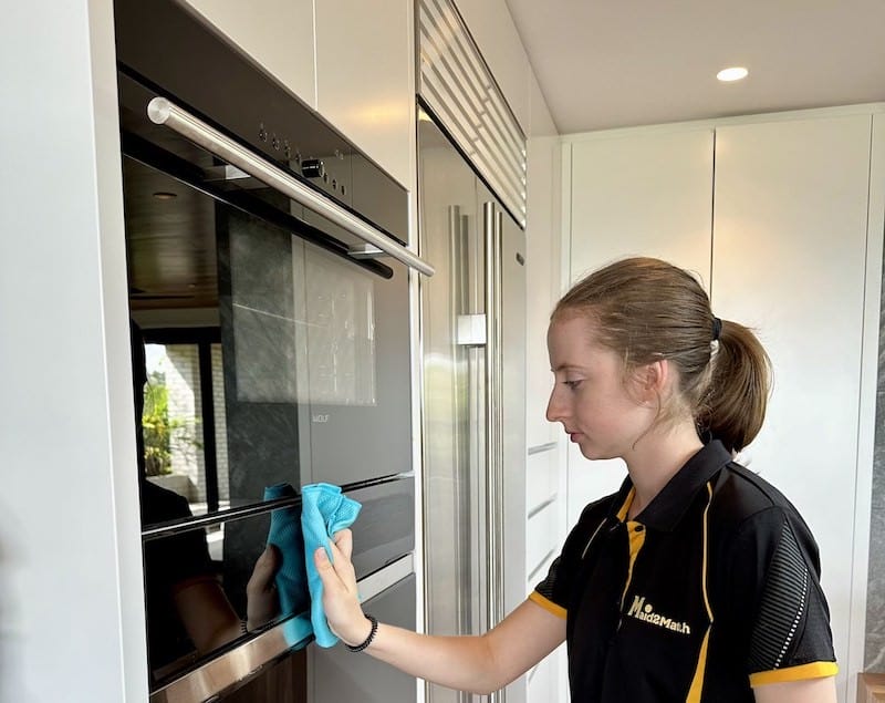 Professional cleaner wiping down oven glass door